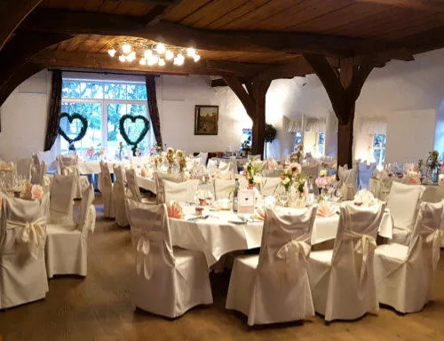 Festlich eingedeckter Saal mit weißen Stuhlhussen