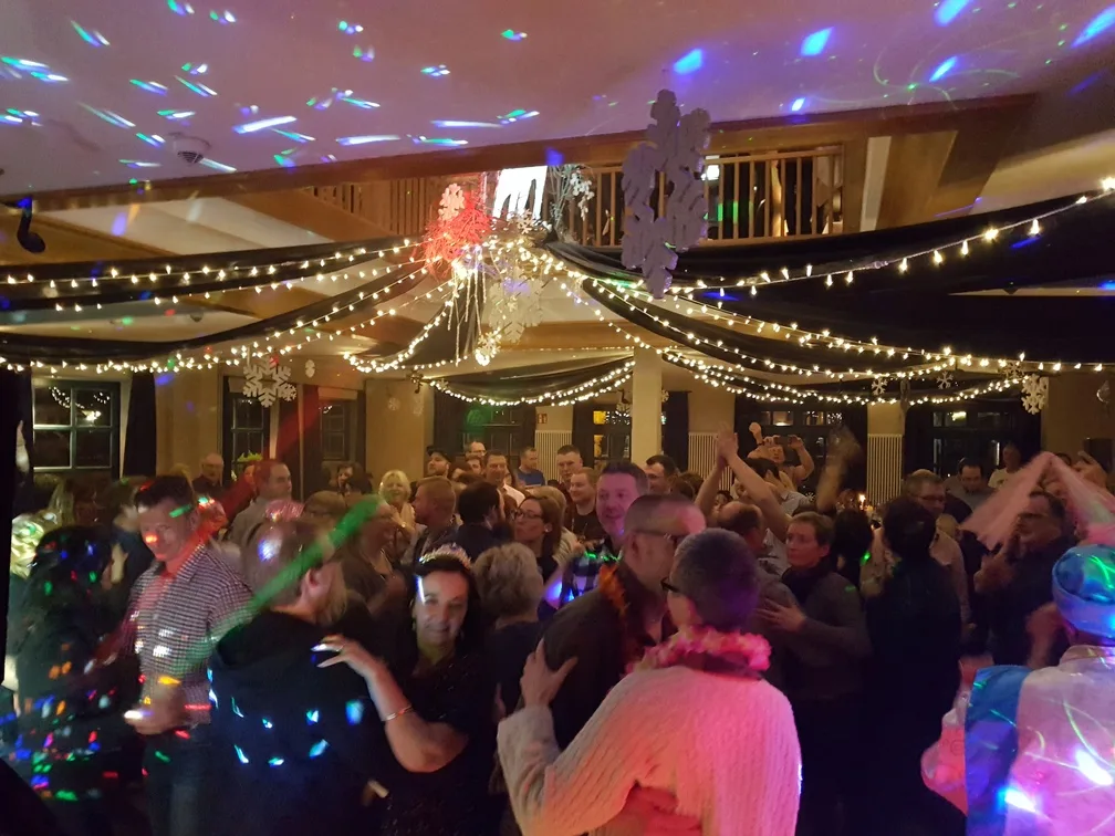 Volle Tanzfläche unter Lichterketten mit Winterdekoration