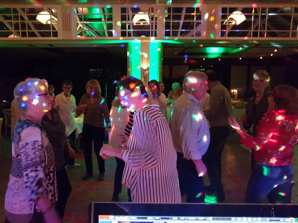 Tanzende Gäste bei bunten Lichtpunkten im hellen Saal