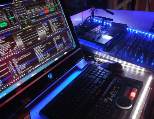 Laptop mit DJ-Software neben beleuchtetem Mischpult